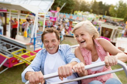 Senior couple having fun on a ride in amusement park.